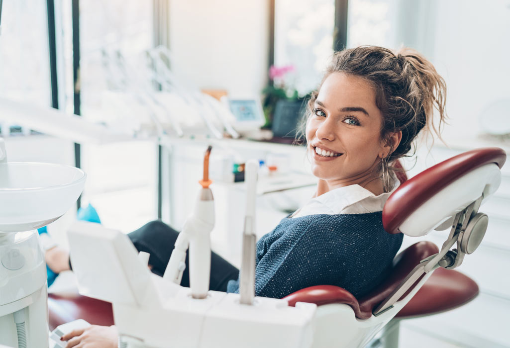 Brunette woman smile in the dental chair after receiving a crown and veneers at the dentist