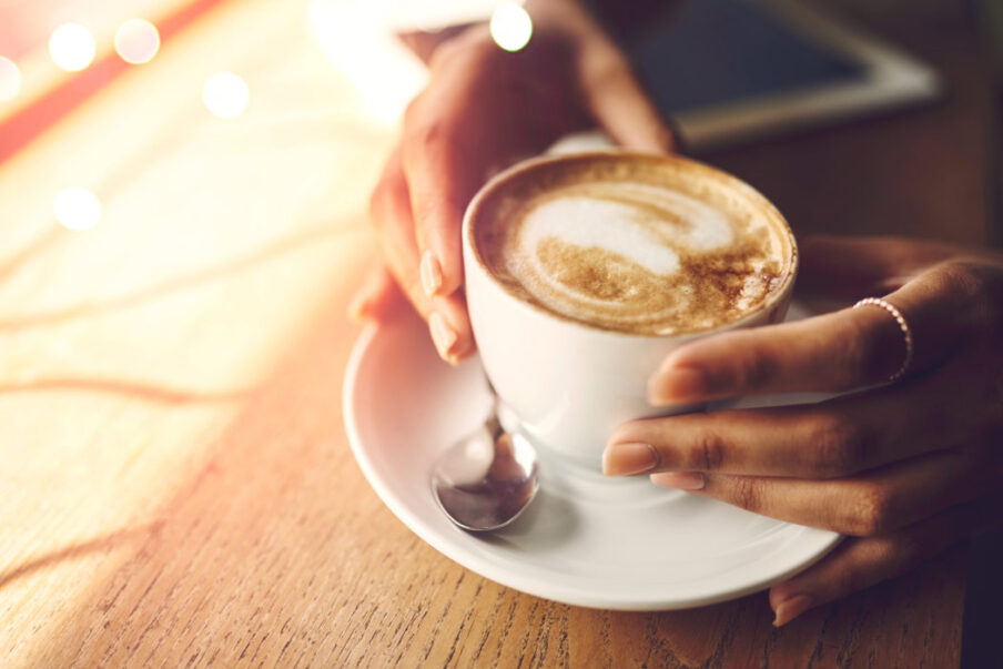 Closeup of woman's hands touching a cup of coffee, a drink that stains teeth